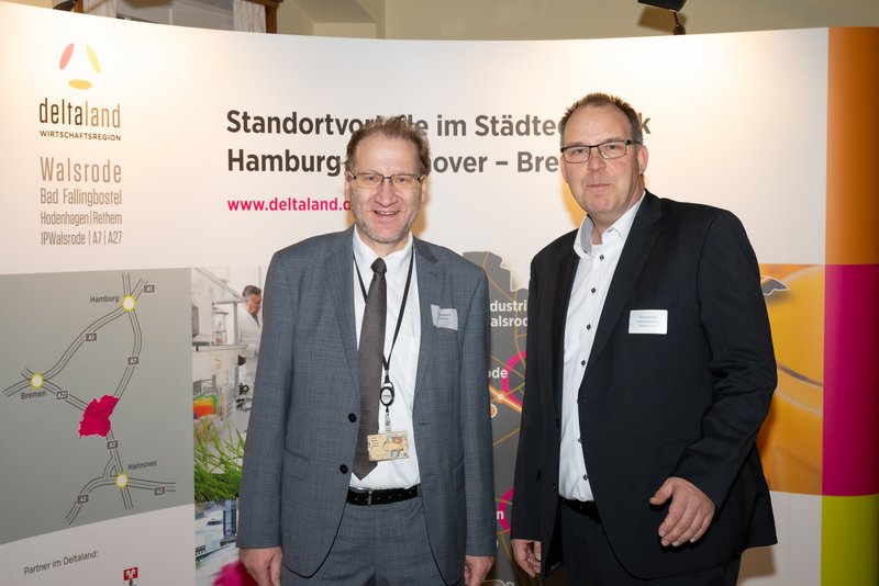 Das Bild zeigt zwei Männer, die lächelnd vor einem Banner stehen, das Informationen über die Region Walsrode enthält. Die Atmosphäre wirkt professionell und freundlich, was auf eine Networking-Veranstaltung hindeutet.