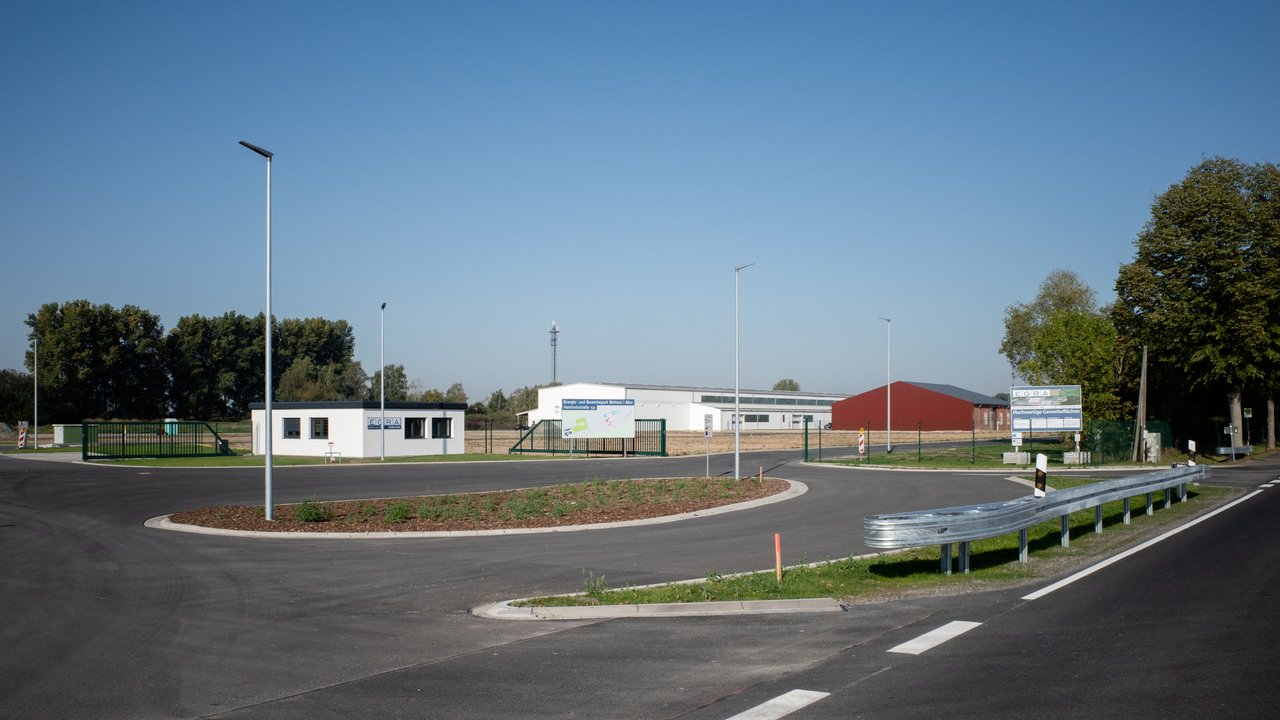  Das Bild zeigt eine moderne Industriezone mit Bürogebäuden, Lagerhallen und einer gut ausgebauten Infrastruktur. Es ist eine Ansicht auf ein Gewerbegebiet mit Straßen, Parkplätzen und Beleuchtung, umgeben von Grünflächen und Bäumen.