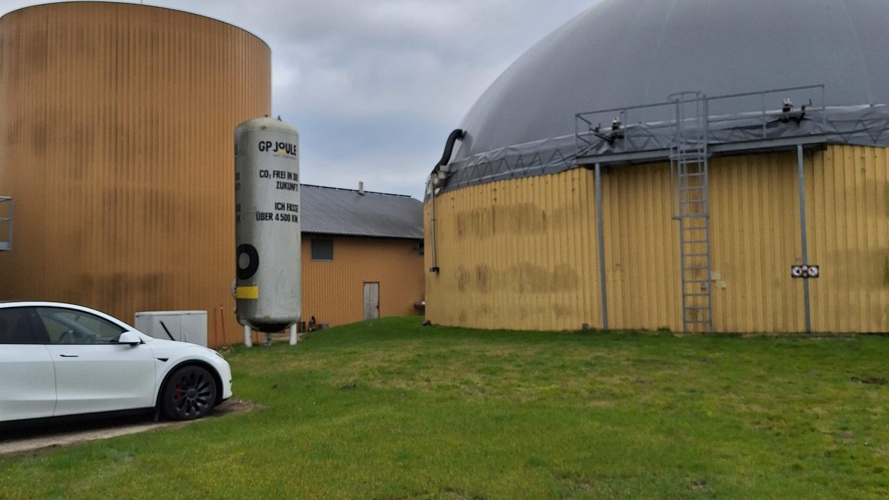 Ein Auto parkt auf dem Gelände von GP Joule neben Biogasanlagen.