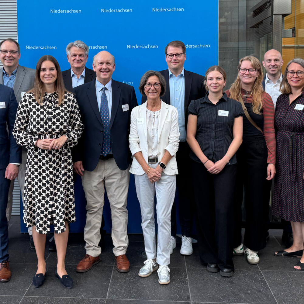 Parlamentarisches Frühstück | Ⓒ Daniel Kipp H2.N.O.N/MCON Vor einem blauen Hintergrund mit dem Logo der Landesvertretung Niedersachsen steht eine Gruppe von Menschen in Businesskleidung und lächelt in die Kamera. Das Foto wirkt offiziell und wurde vermutlich im Rahmen eines parlamentarischen Frühstücks oder einer politischen Veranstaltung aufgenommen.