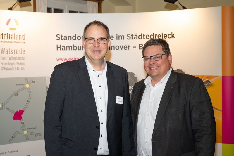 Das Bild zeigt zwei Männer, die lächelnd vor einem Banner stehen, das Informationen über die Region Walsrode enthält. Die Atmosphäre wirkt professionell und freundlich, was auf eine Networking-Veranstaltung hindeutet.